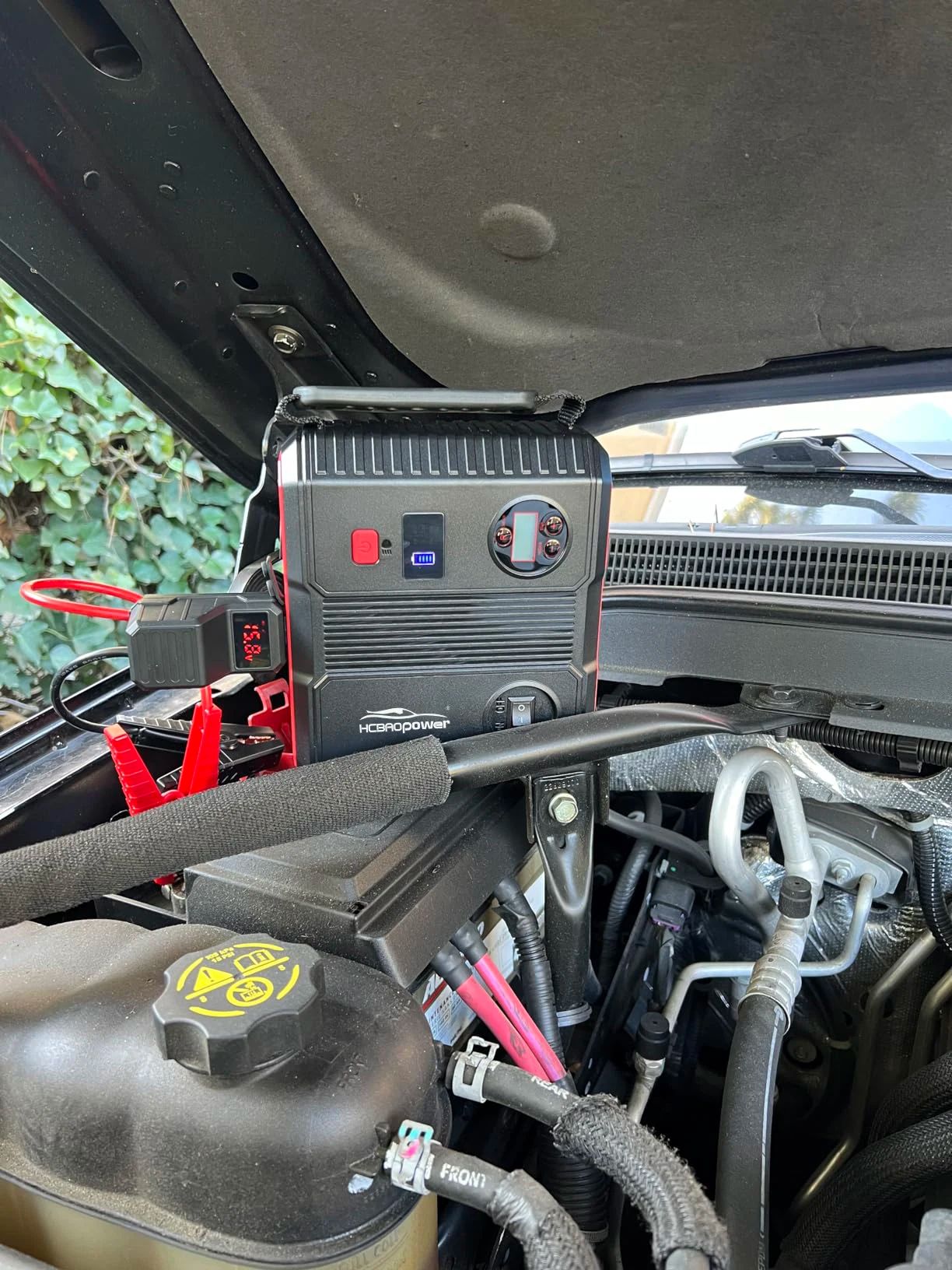 Driver using a portable jump starter on a highway, avoiding the need for road side assistance waiting times.
